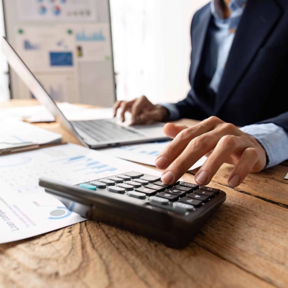 businessman working on desk office with using a calculator to calculate the numbers, finance accounting concept.