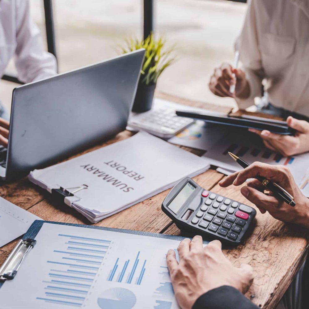 Young colleagues discussing business and price chart analyzes business people on the table great in modern coworking office teamwork concept. Calculate personal tax for customers